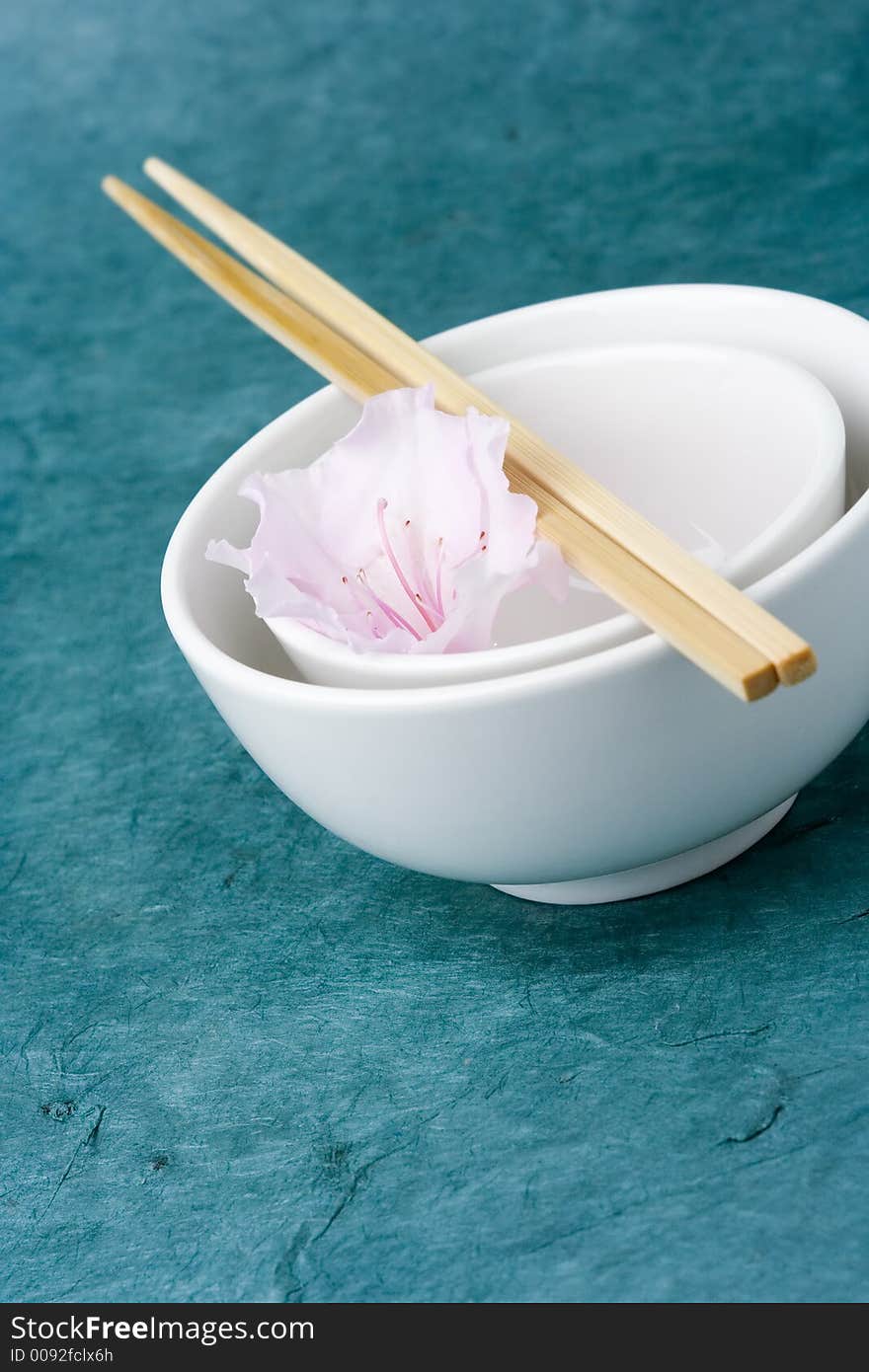 Chinese rice bowls against a textured background with a single azalea flower for styling. Chinese rice bowls against a textured background with a single azalea flower for styling.