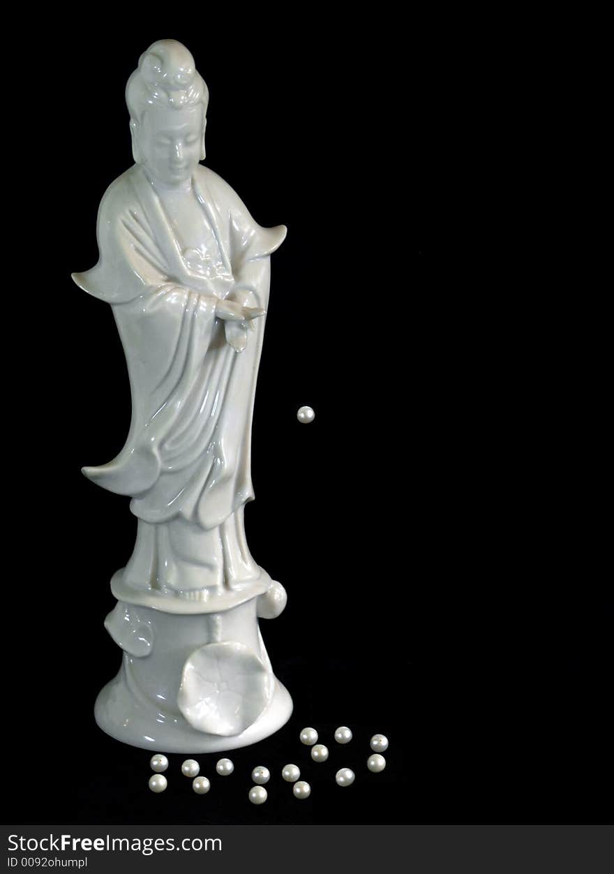 White porcelain Chinese female figure with pearls at her feet and one pearl suspended in the air isolated on black background. White porcelain Chinese female figure with pearls at her feet and one pearl suspended in the air isolated on black background