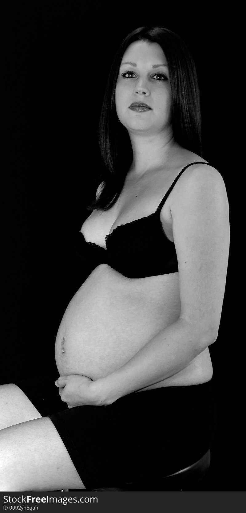 A pregnant lady shot on black.  Expression is of concern