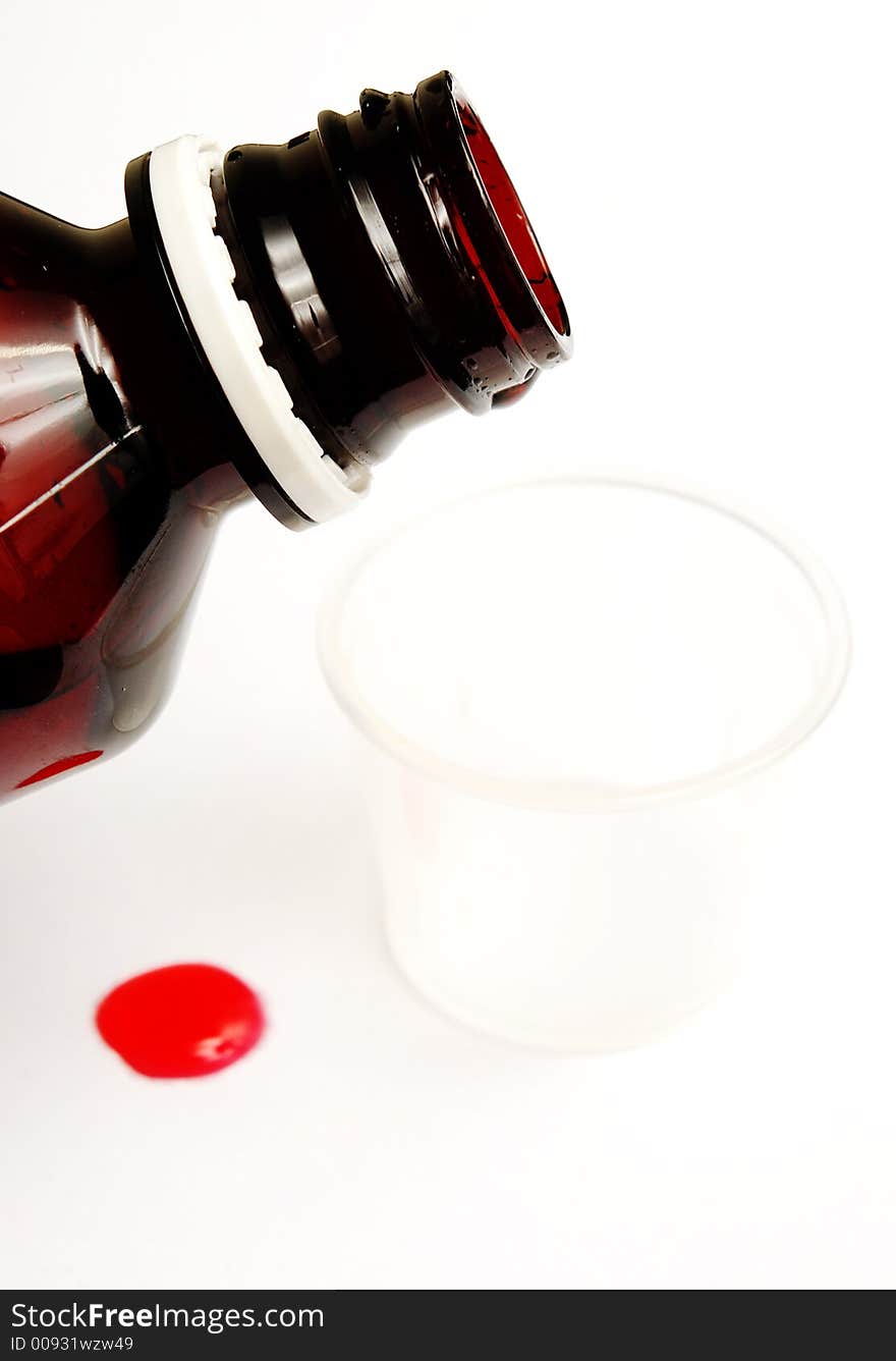 Measuring cough syrup with spilled drop on white background. Measuring cough syrup with spilled drop on white background