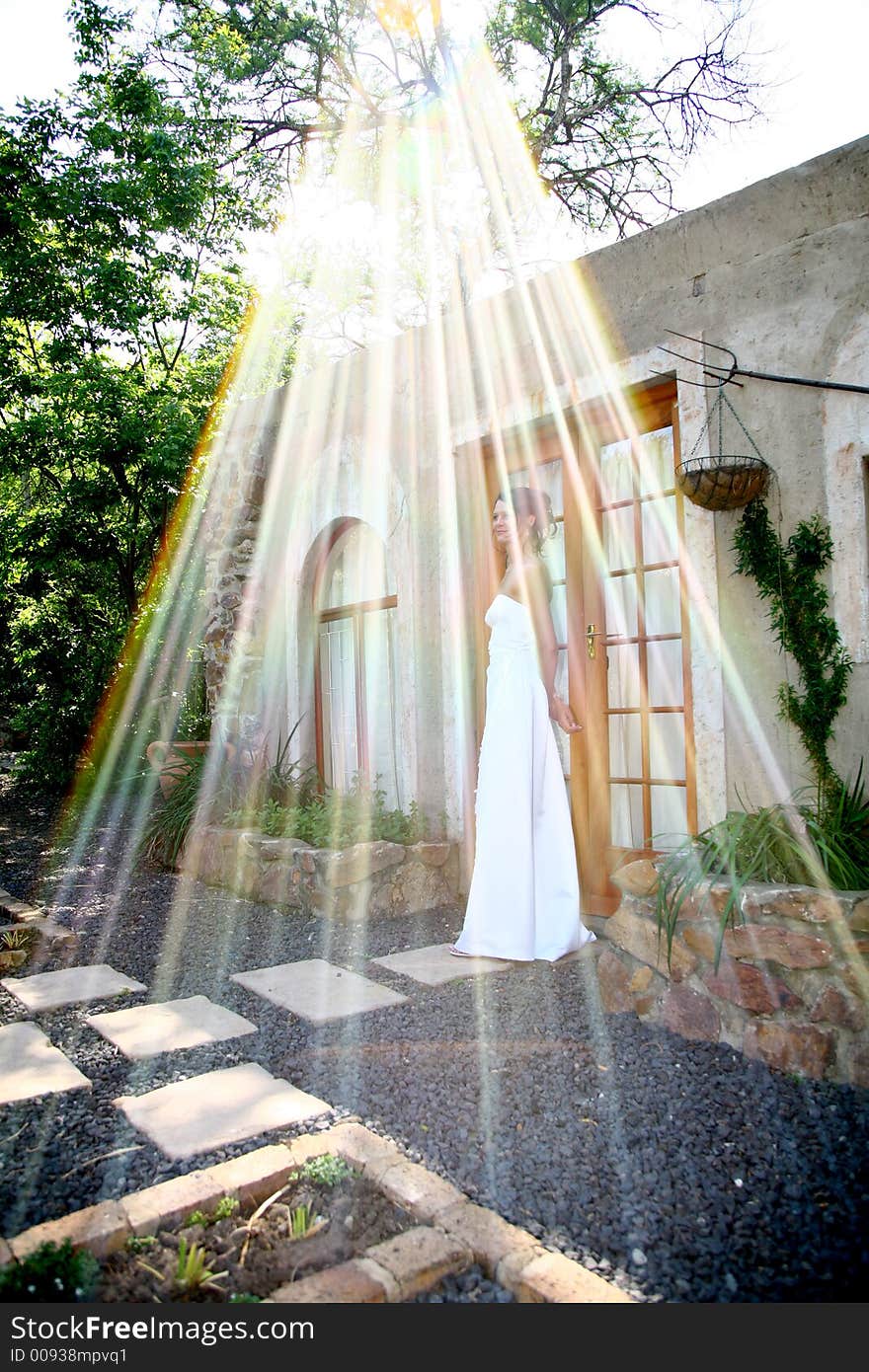 A bride standing outside and sunrays shining down on her. A bride standing outside and sunrays shining down on her