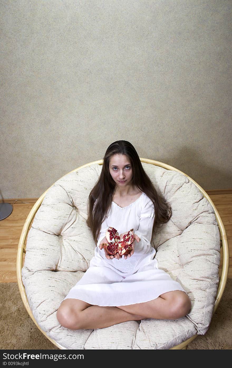 Woman sitting in an armchair with fruit in hands. Woman sitting in an armchair with fruit in hands