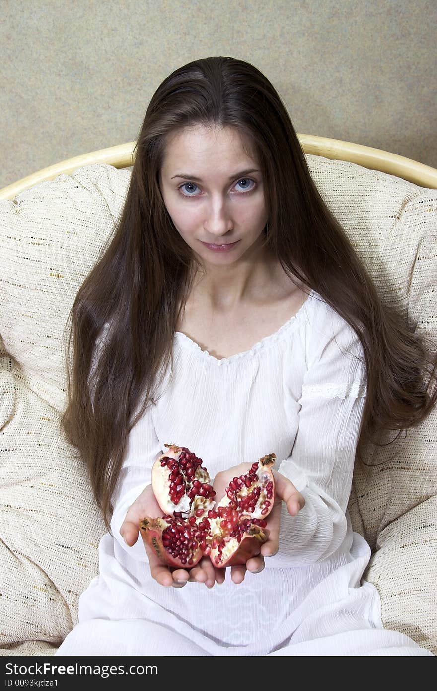 Woman sitting in an armchair with fruit in hands. Woman sitting in an armchair with fruit in hands