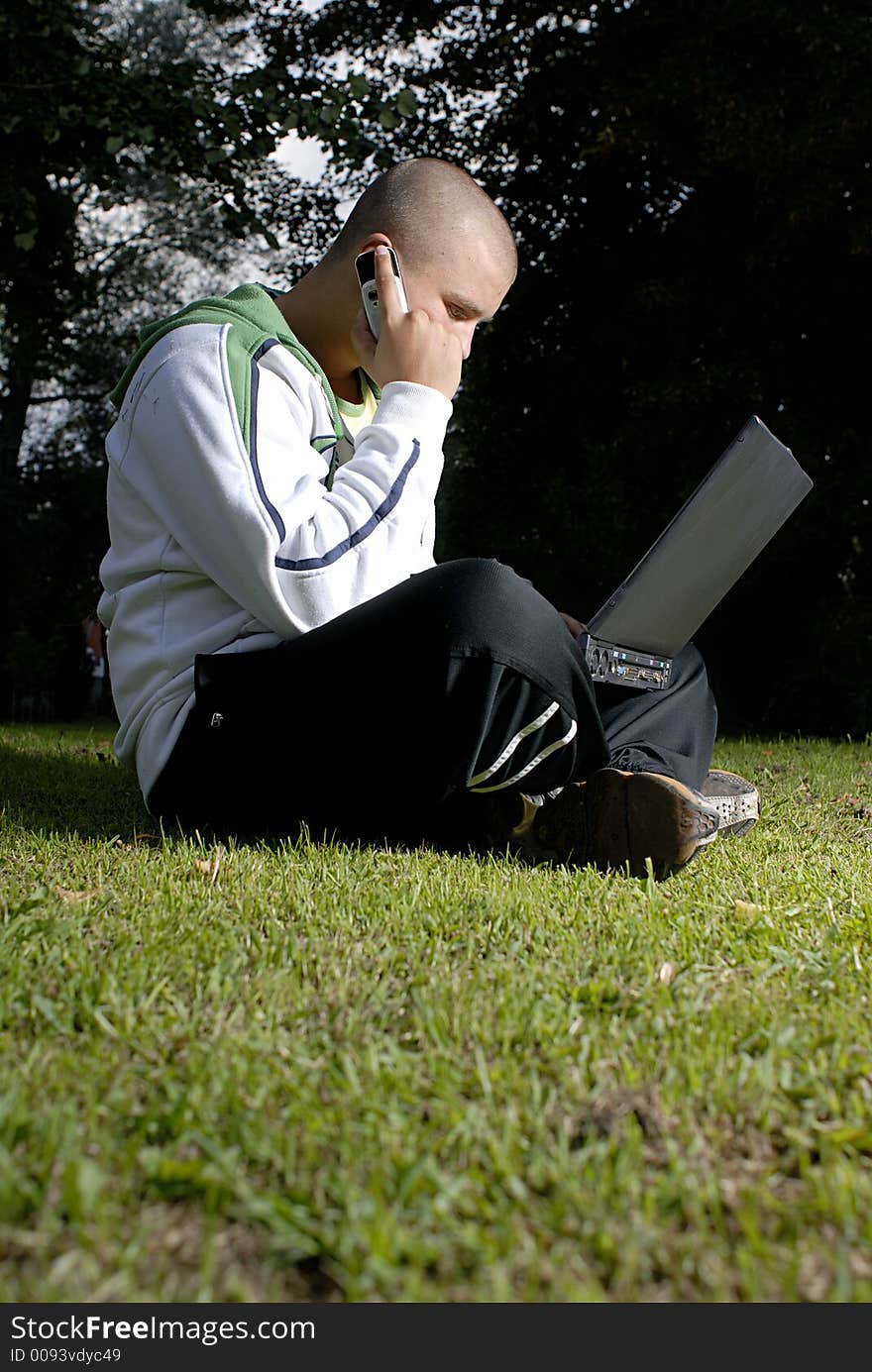 Boy with notebook and cell phone in park