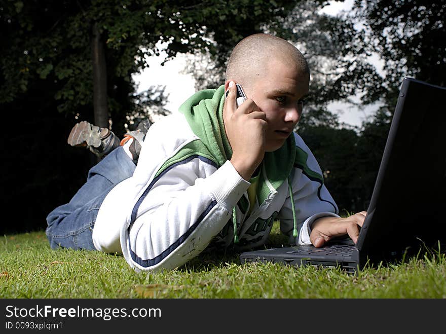 Picture of boy with notebook and cell phone in park