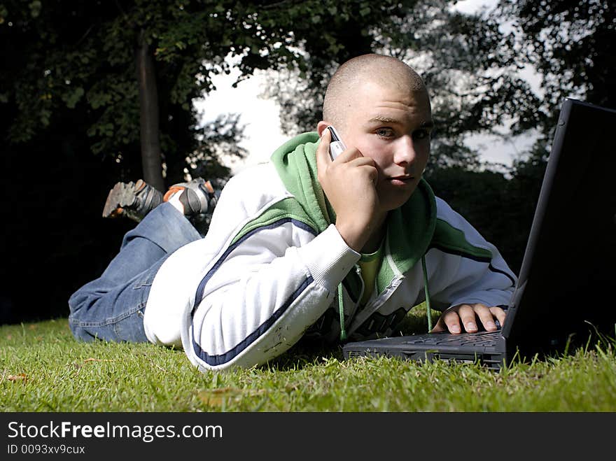 Picture of boy with notebook and cell phone in park