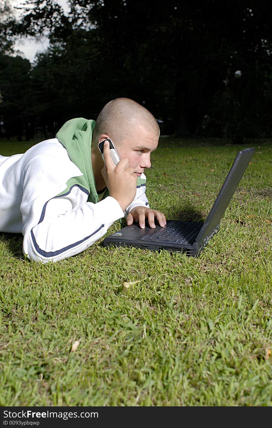 Boy with notebook and cell phone in park