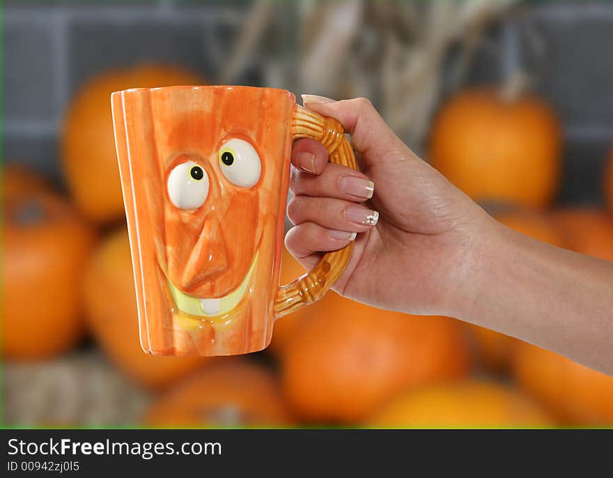 A woman holding a pumpkin shaped coffee mug. A woman holding a pumpkin shaped coffee mug