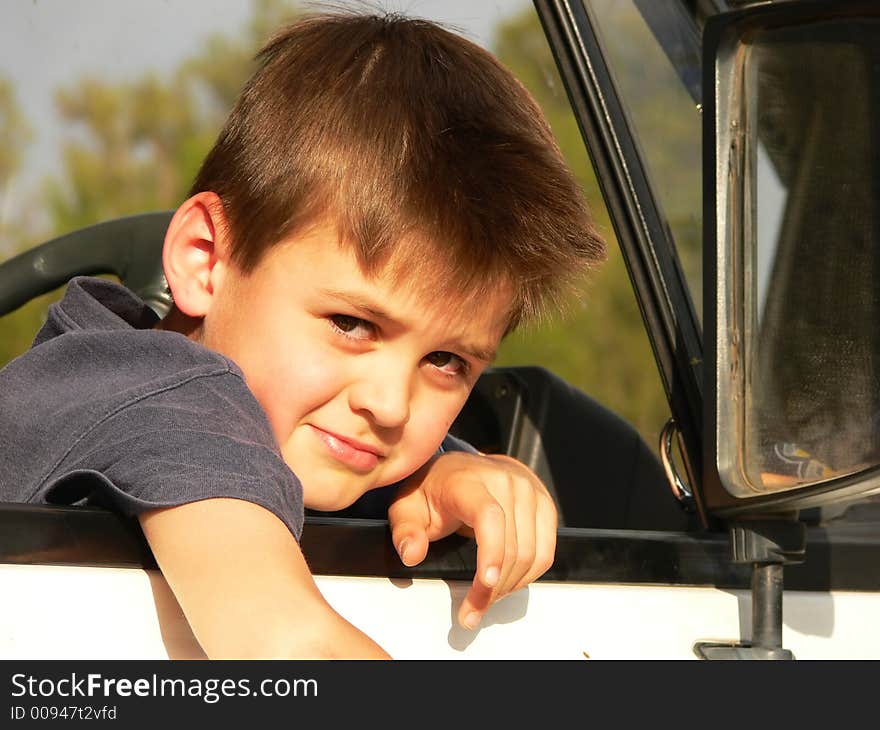 A boy sitting in the drivers seat of a vehicle. A boy sitting in the drivers seat of a vehicle