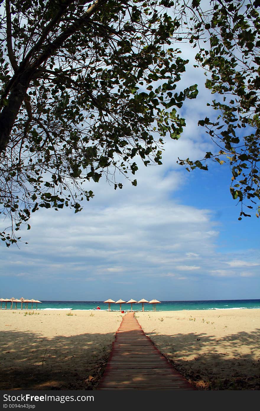 Two sun loungers and beach umbrella blue water sea waves. Two sun loungers and beach umbrella blue water sea waves