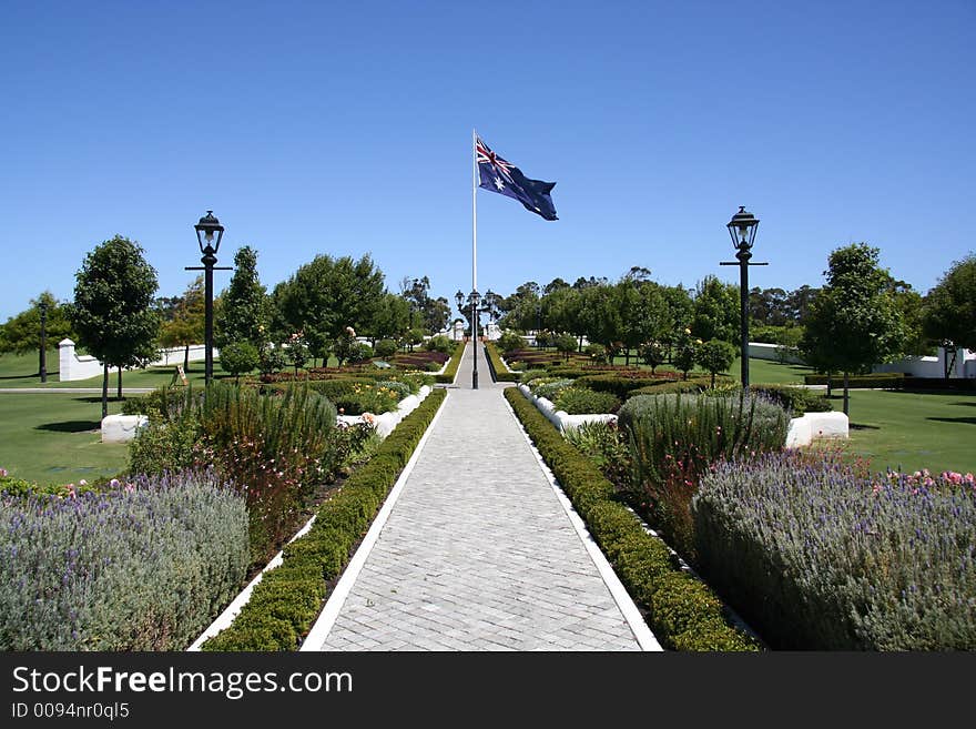 A cottage garden path leads to a big Australian flag blowing in the wind. A cottage garden path leads to a big Australian flag blowing in the wind