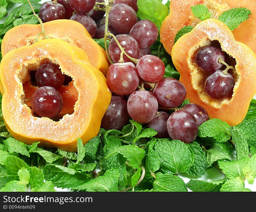 Papaya sliced whit red grapes on mint leaves