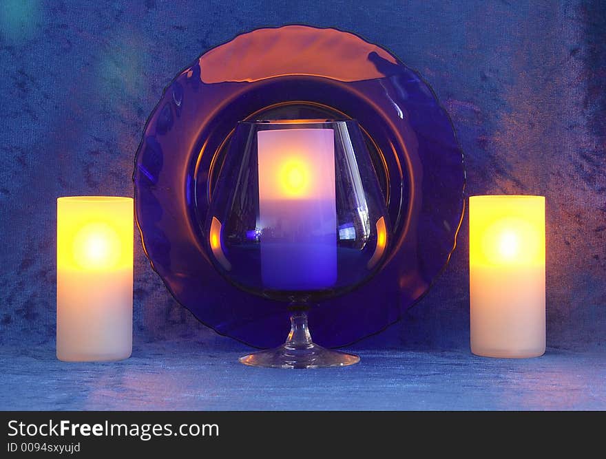 Blue Goblet,candles,plate.Blue background. Blue Goblet,candles,plate.Blue background