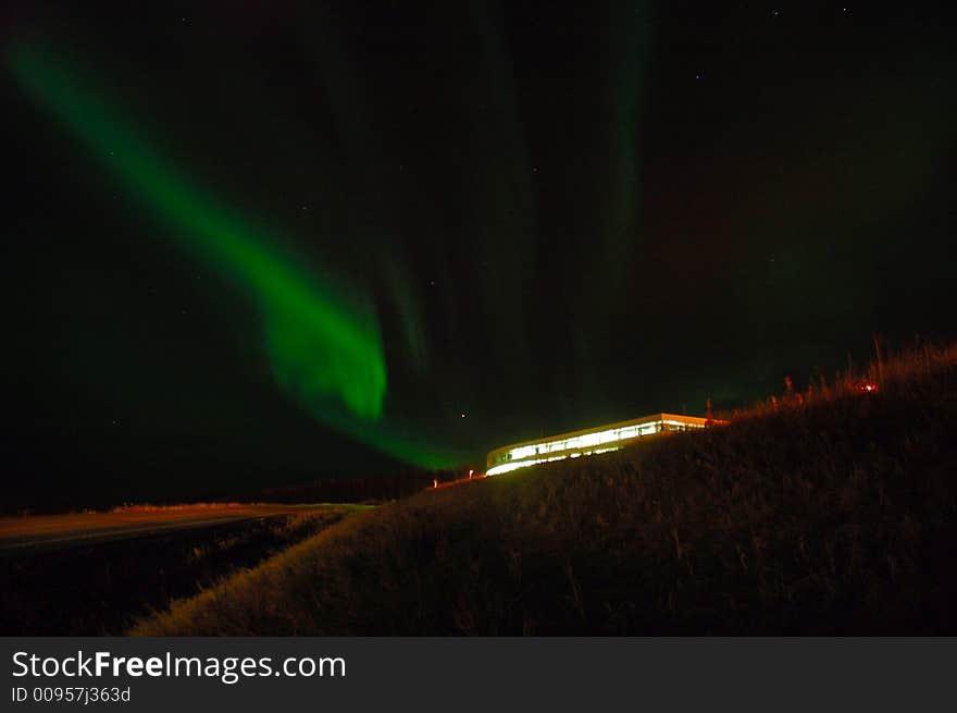 Northern lights over a lit up building. Northern lights over a lit up building.