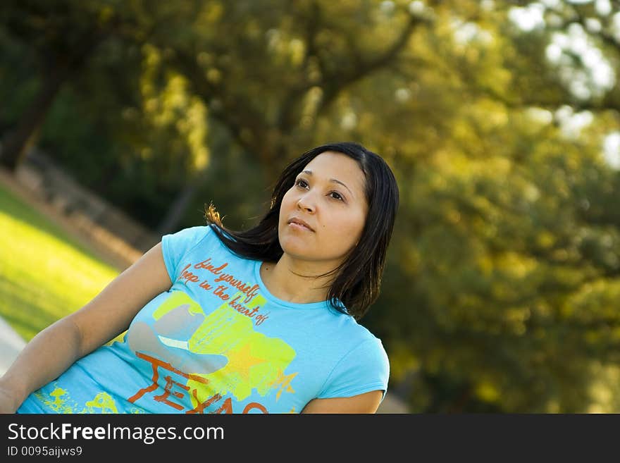 Half body of a girl sitting with green tree park background. Half body of a girl sitting with green tree park background