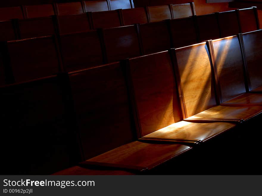 Rows of church pews with stream of light illuminating a seat