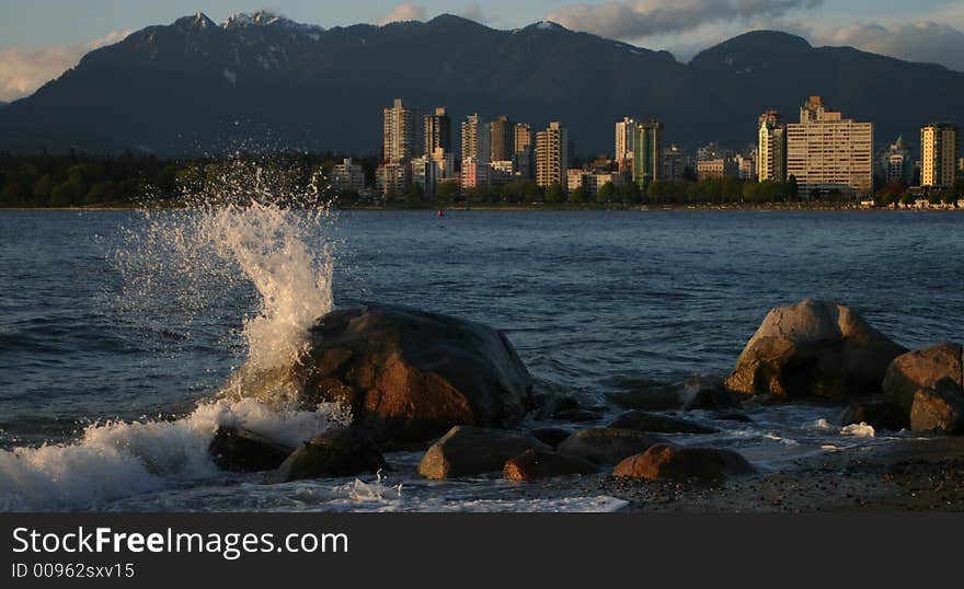 Wave hitting rock with vancouver in background. Wave hitting rock with vancouver in background