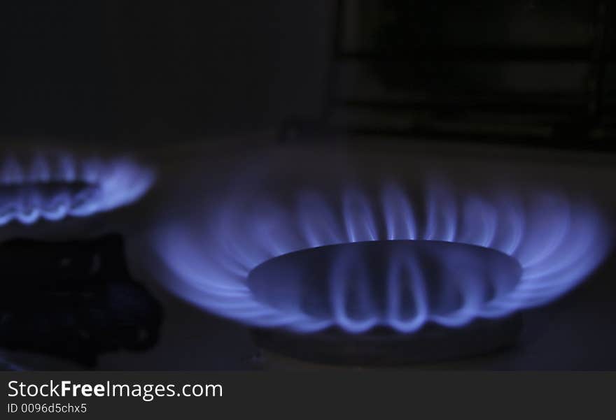 The flame of a gas-stove in the dark of a kitchen. The flame of a gas-stove in the dark of a kitchen