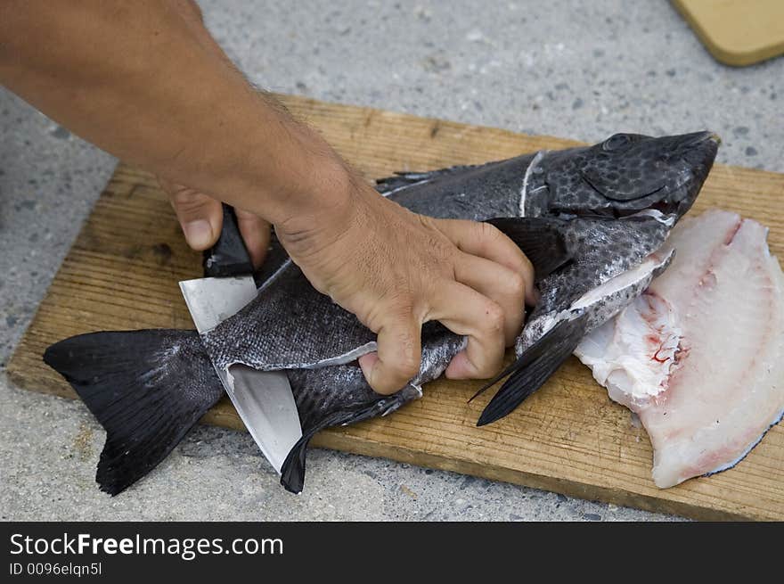 A man cutting and preparing a fish for eating. A man cutting and preparing a fish for eating