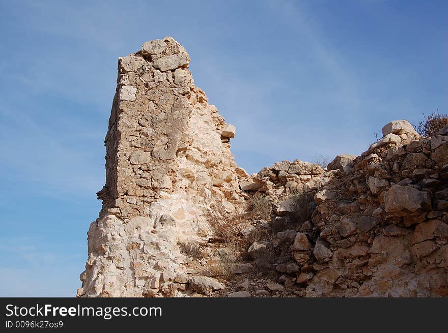 Grandella castle in ruins in spain showing a part of the walls with a blue sky and white whispy cloud lines. Grandella castle in ruins in spain showing a part of the walls with a blue sky and white whispy cloud lines