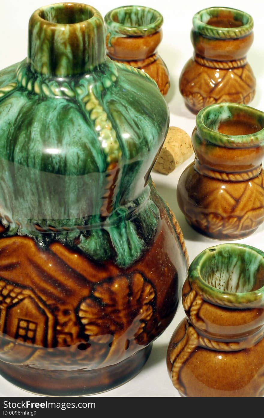 This is a close up image of a ceramic liquor bottle and shot glasses. This is a close up image of a ceramic liquor bottle and shot glasses.