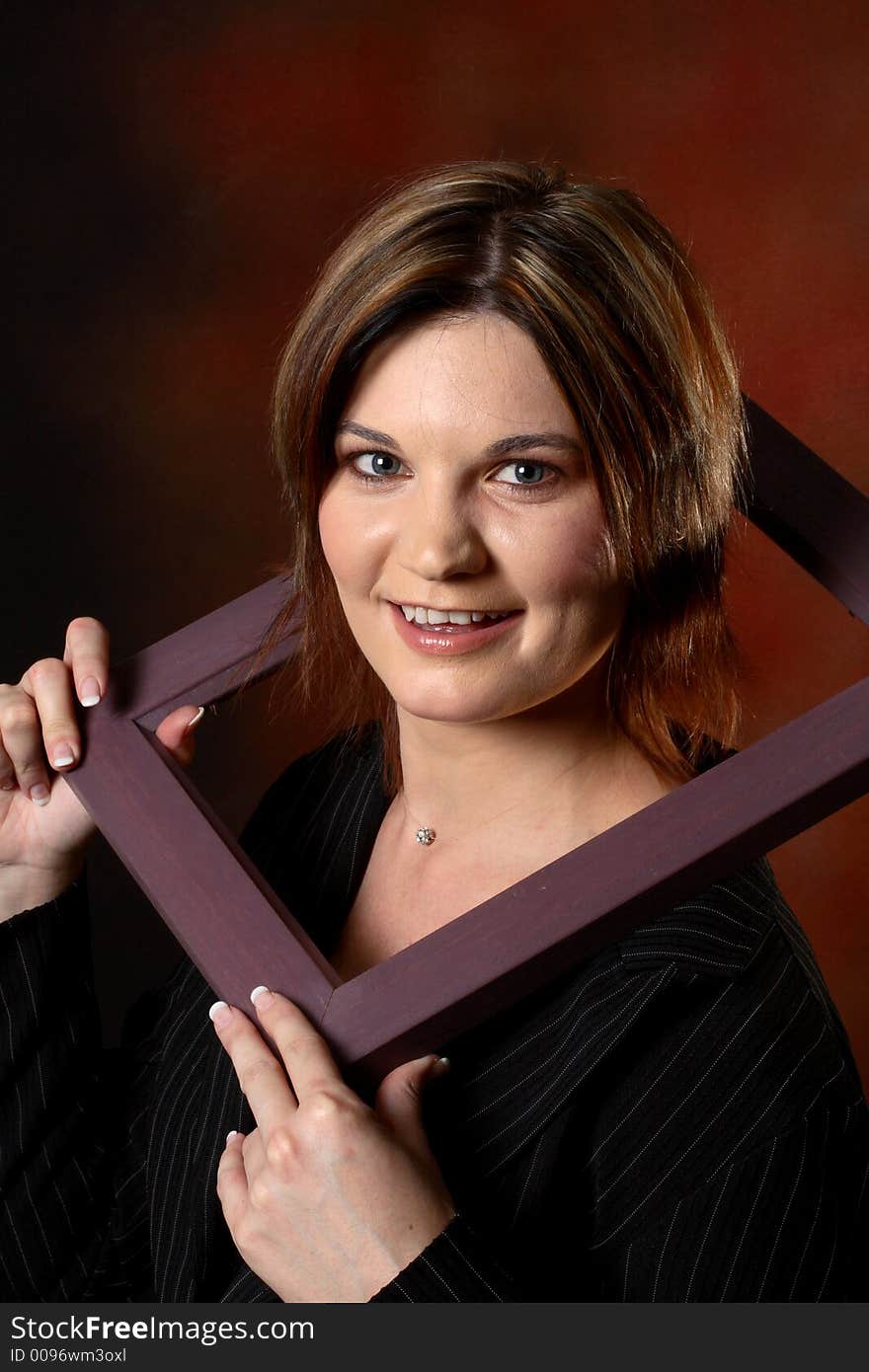 Brunette girl using a picture frame to frame her face. Brunette girl using a picture frame to frame her face