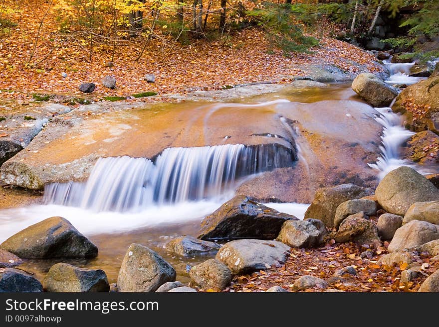 Water fallin g over brown boulders. Water fallin g over brown boulders