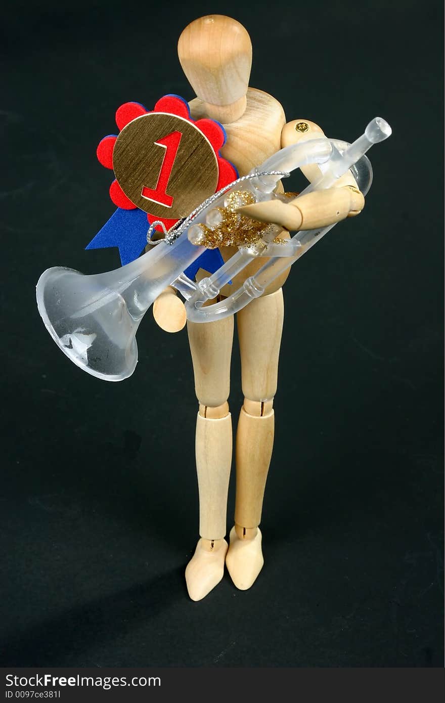 Wooden mannequin holding trumpet and wearing winning ribbon. Wooden mannequin holding trumpet and wearing winning ribbon