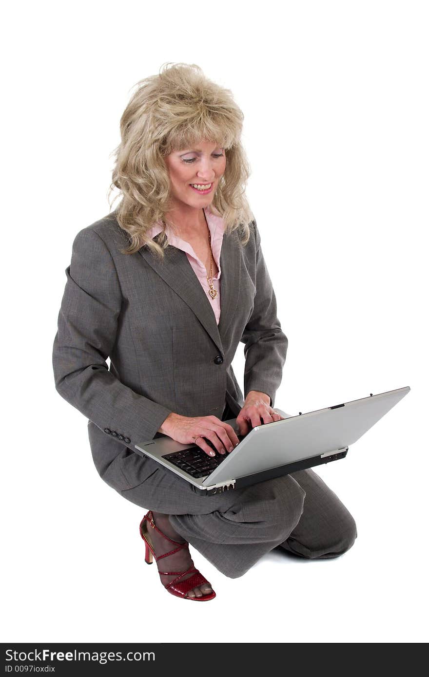 Attractive executive business woman kneeling while working on a laptop computer. Attractive executive business woman kneeling while working on a laptop computer.