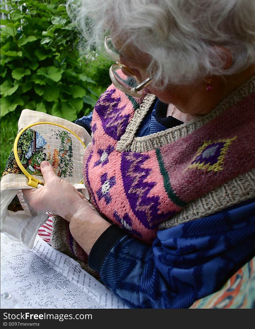 The elderly woman embroiders. Close-up. The elderly woman embroiders. Close-up.