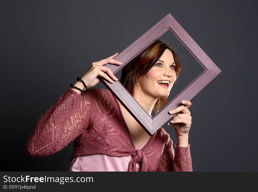 Brunette girl using a picture frame to frame her face. Brunette girl using a picture frame to frame her face