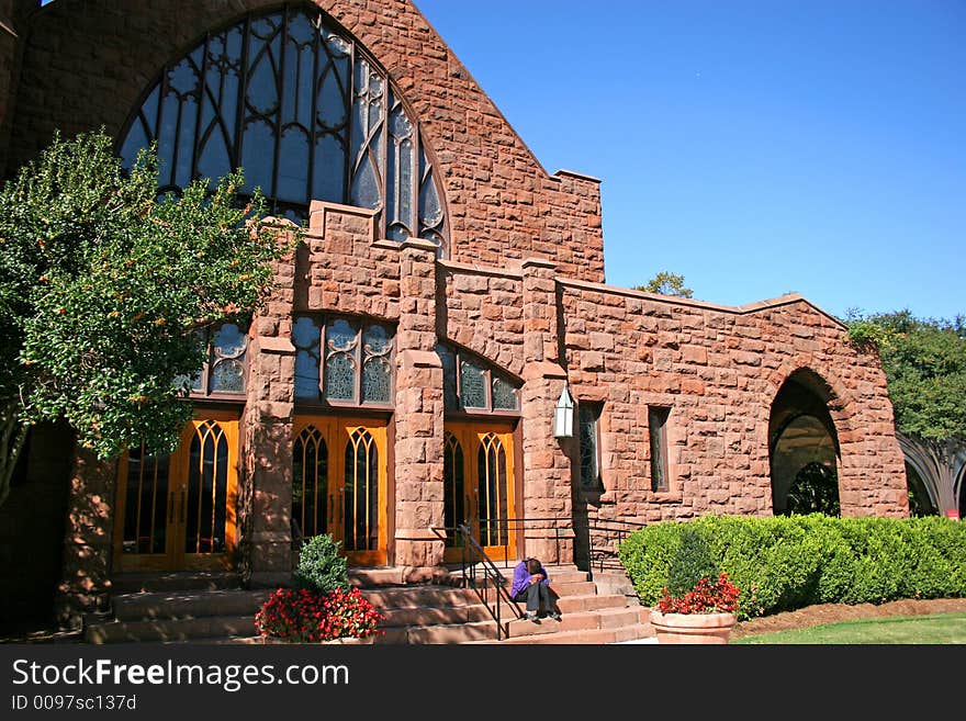 A homeless person sitting on steps of church with head in hands. A homeless person sitting on steps of church with head in hands