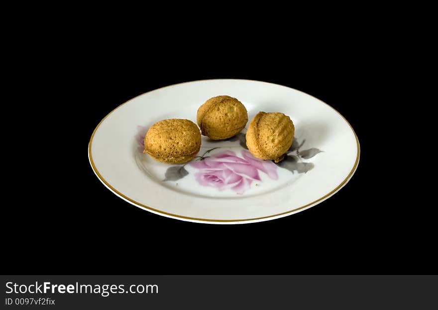 Sweet nutlets on a plate, isolated on black