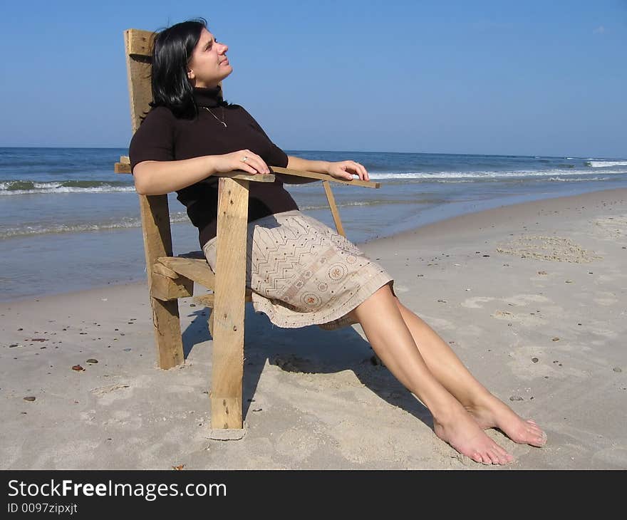 Girl and wooden chair on the beach