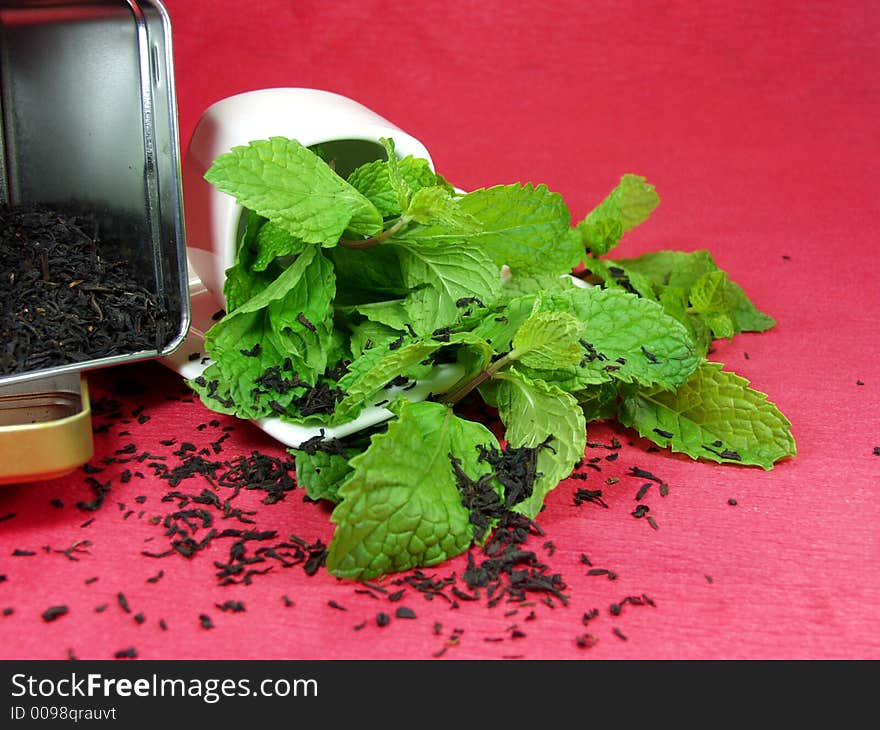 A cup of green tea whit mint leaves on red background