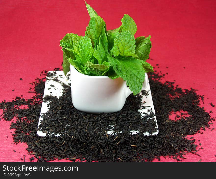 A cup of green tea whit mint leaves on red background