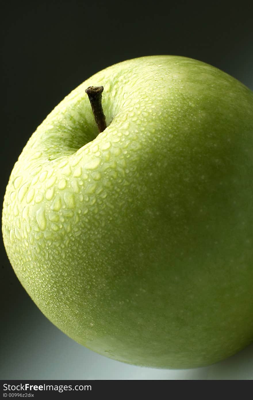 Green apple with water drops close up