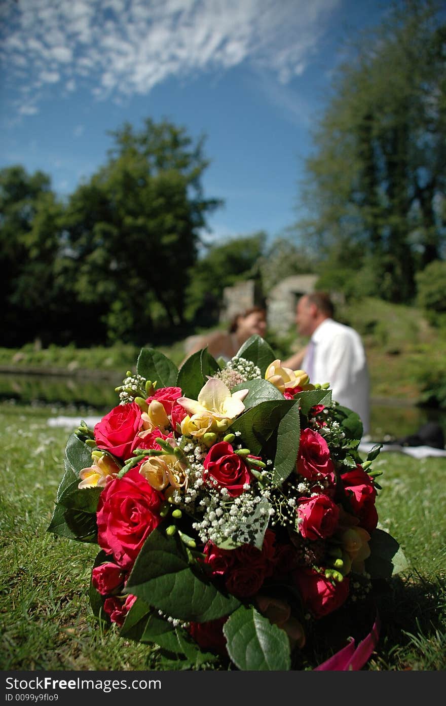 Bouguet in focus. Wedding couple in blur. Bouguet in focus. Wedding couple in blur