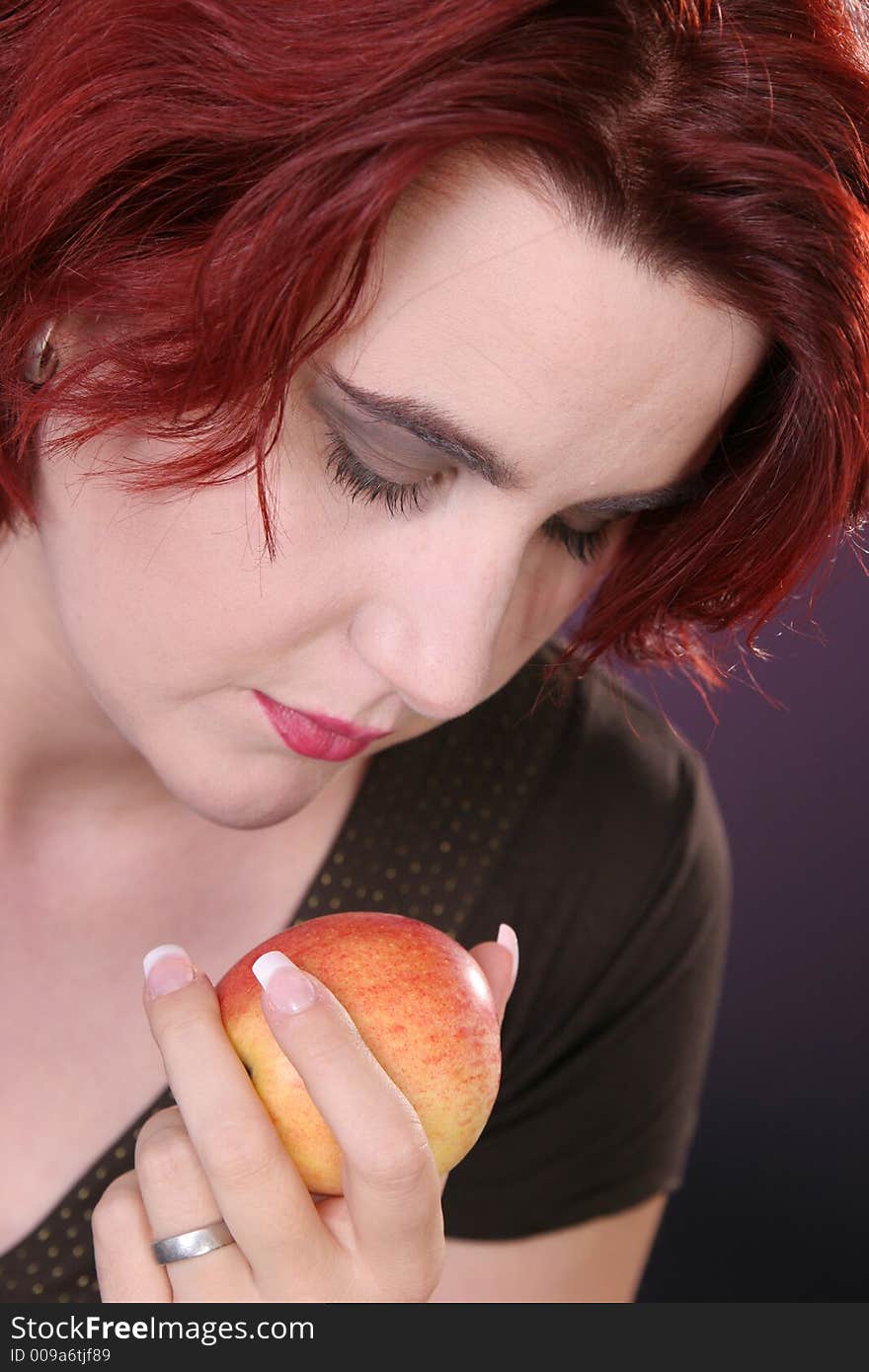 Beautiful girl looking at a fresh apple. Beautiful girl looking at a fresh apple