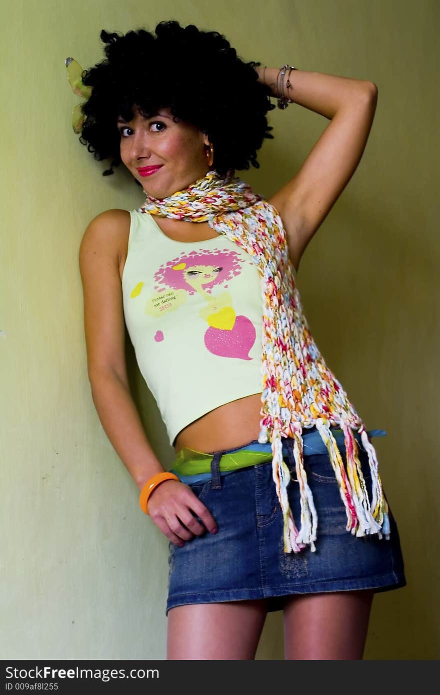 Cute curly disco girl in scarf posing on green background