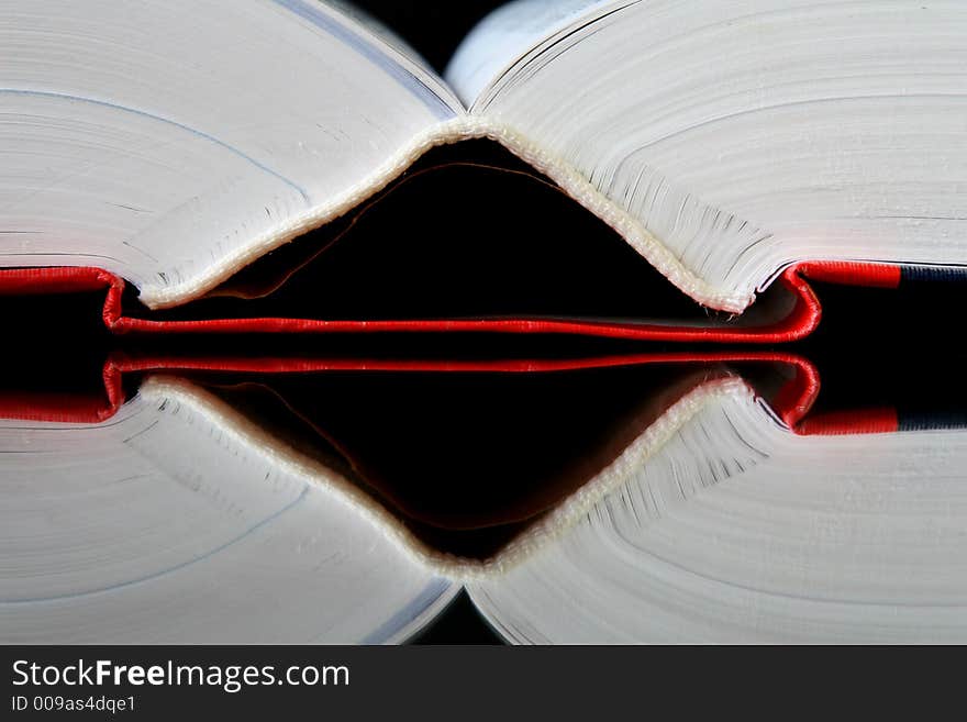 Spine of an opening book on the mirror with black background. Spine of an opening book on the mirror with black background.