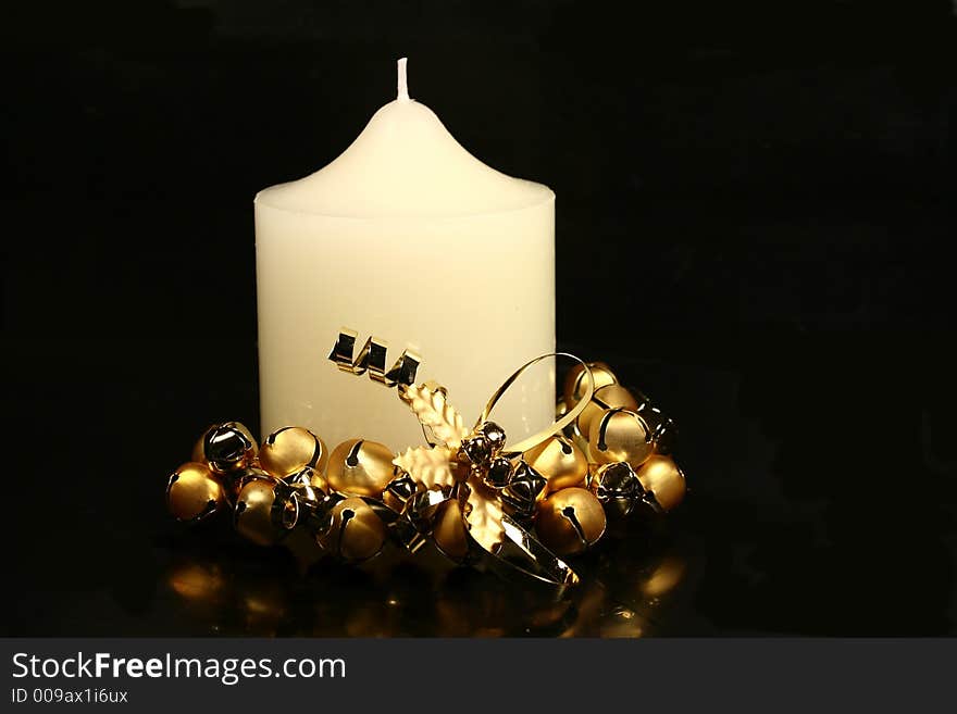 White Christmas church candle with gold bell base on black background. White Christmas church candle with gold bell base on black background.