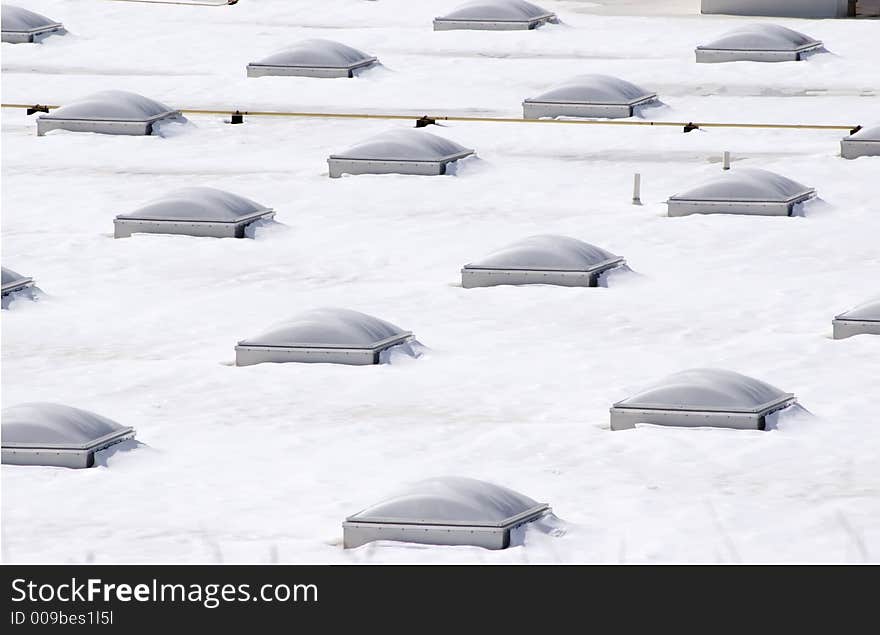 Snow covered rooftop with rows of multiple domed skylights. Snow covered rooftop with rows of multiple domed skylights