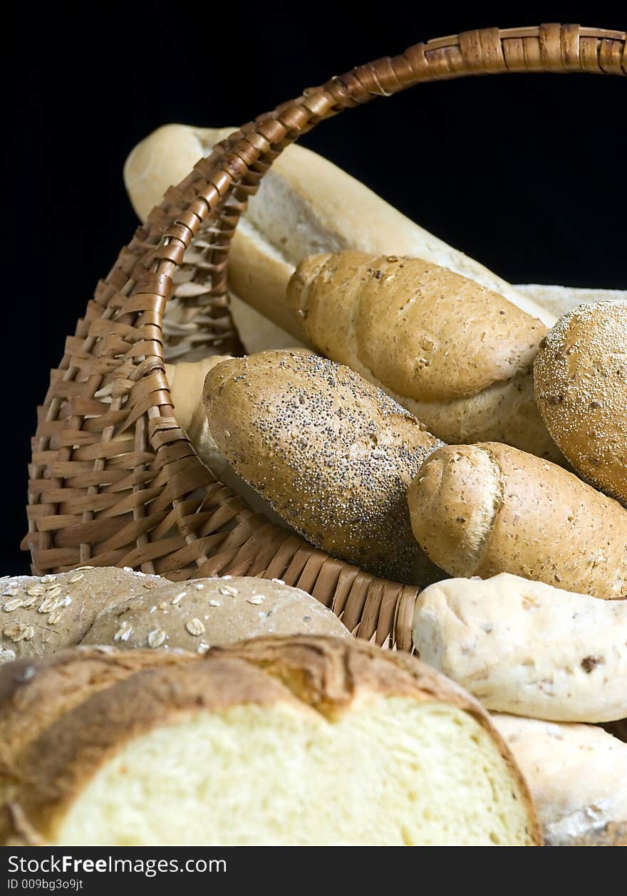 An assortment of breads in a basket with a black background. An assortment of breads in a basket with a black background