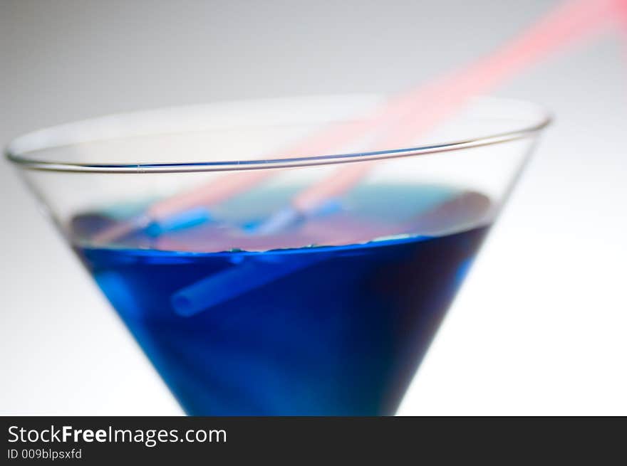 Close up shot of a blue cocktail with pink straws