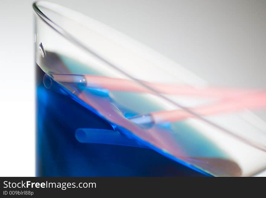 Close up shot of a blue cocktail with pink straws