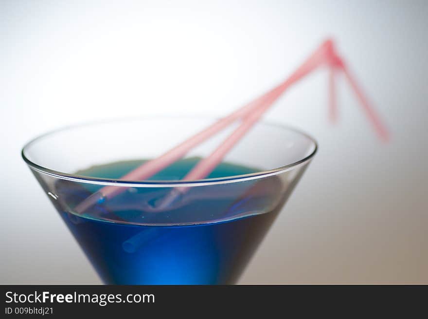 Close up shot of a blue cocktail with pink straws