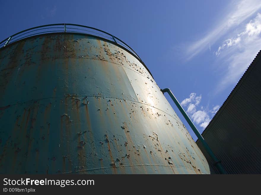 Peeling paint on an industrial tank against the sky