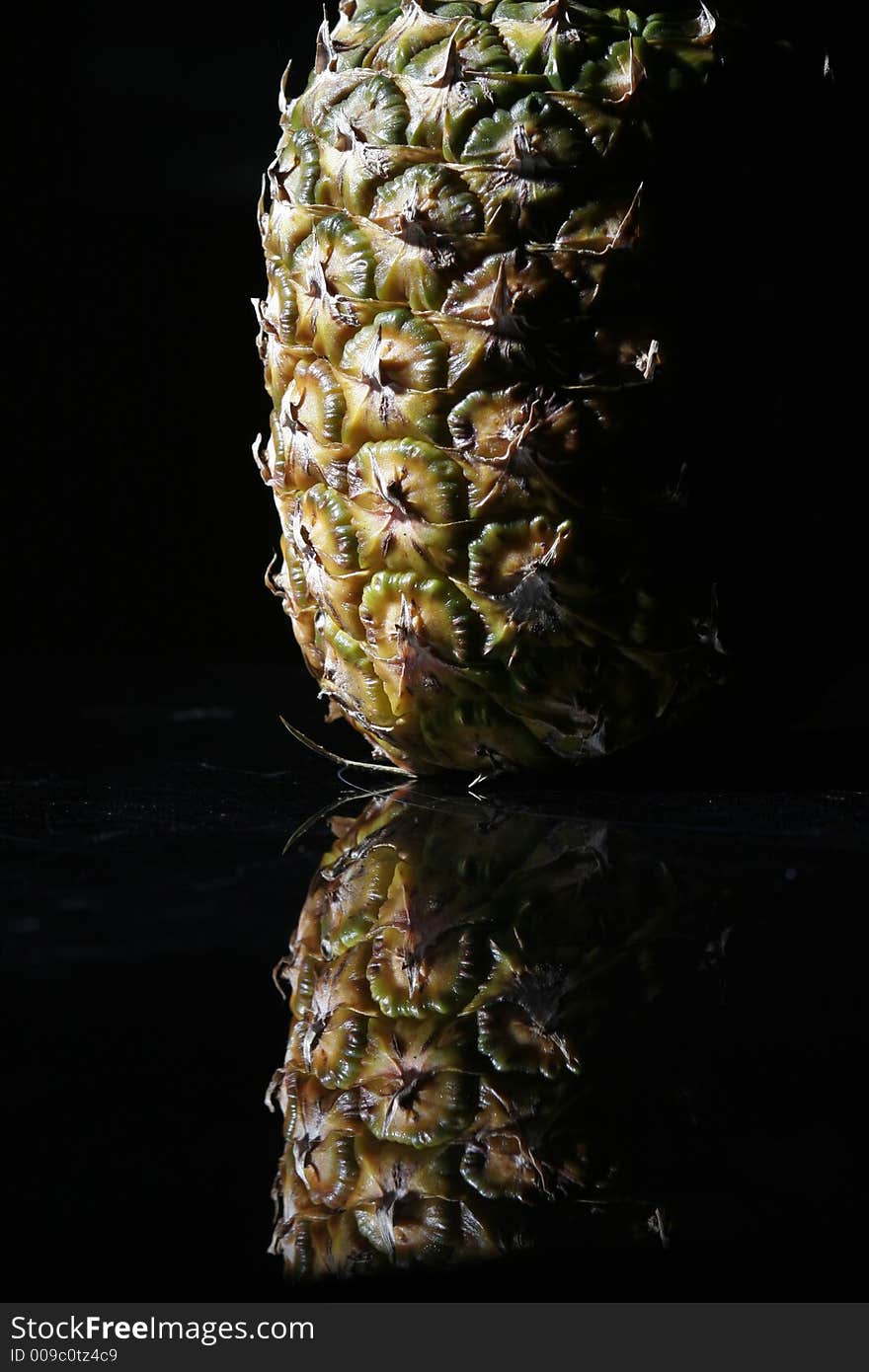 Pineapple on black background reflecting on black surface