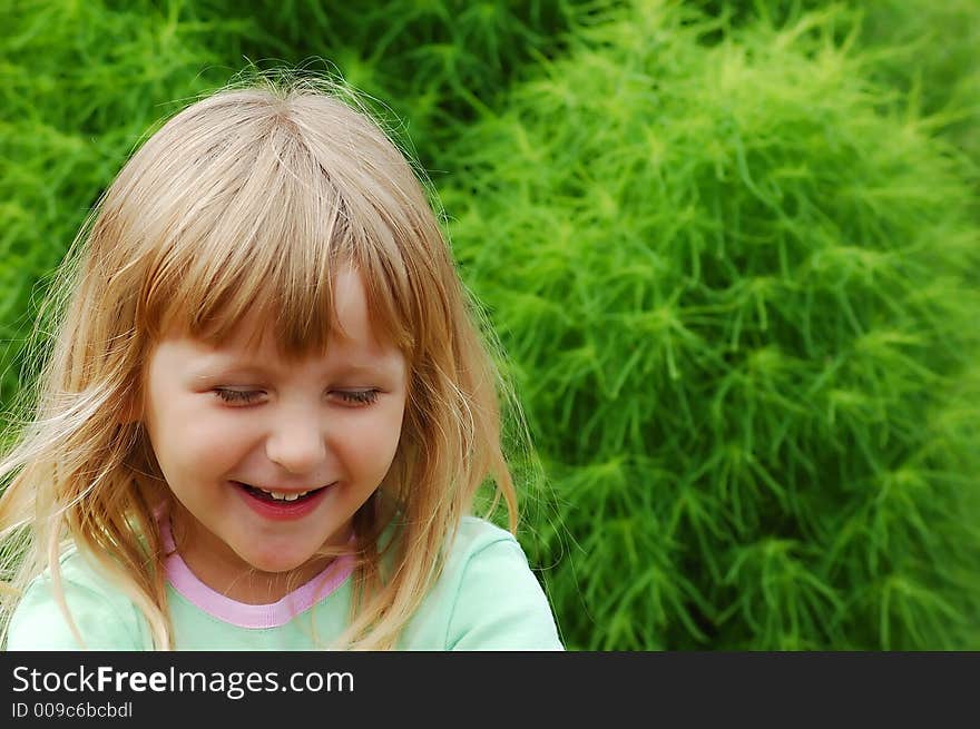 Girl in a garden having fun in front of green bush